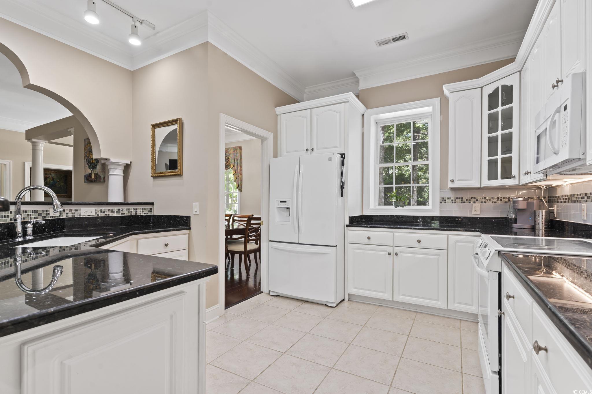 4495 Trotters Court Murrells Inlet, SC 29576 - Photo 25 of 29 Kitchen with white appliances, ornate columns, crown molding, backsplash, and arched walkways