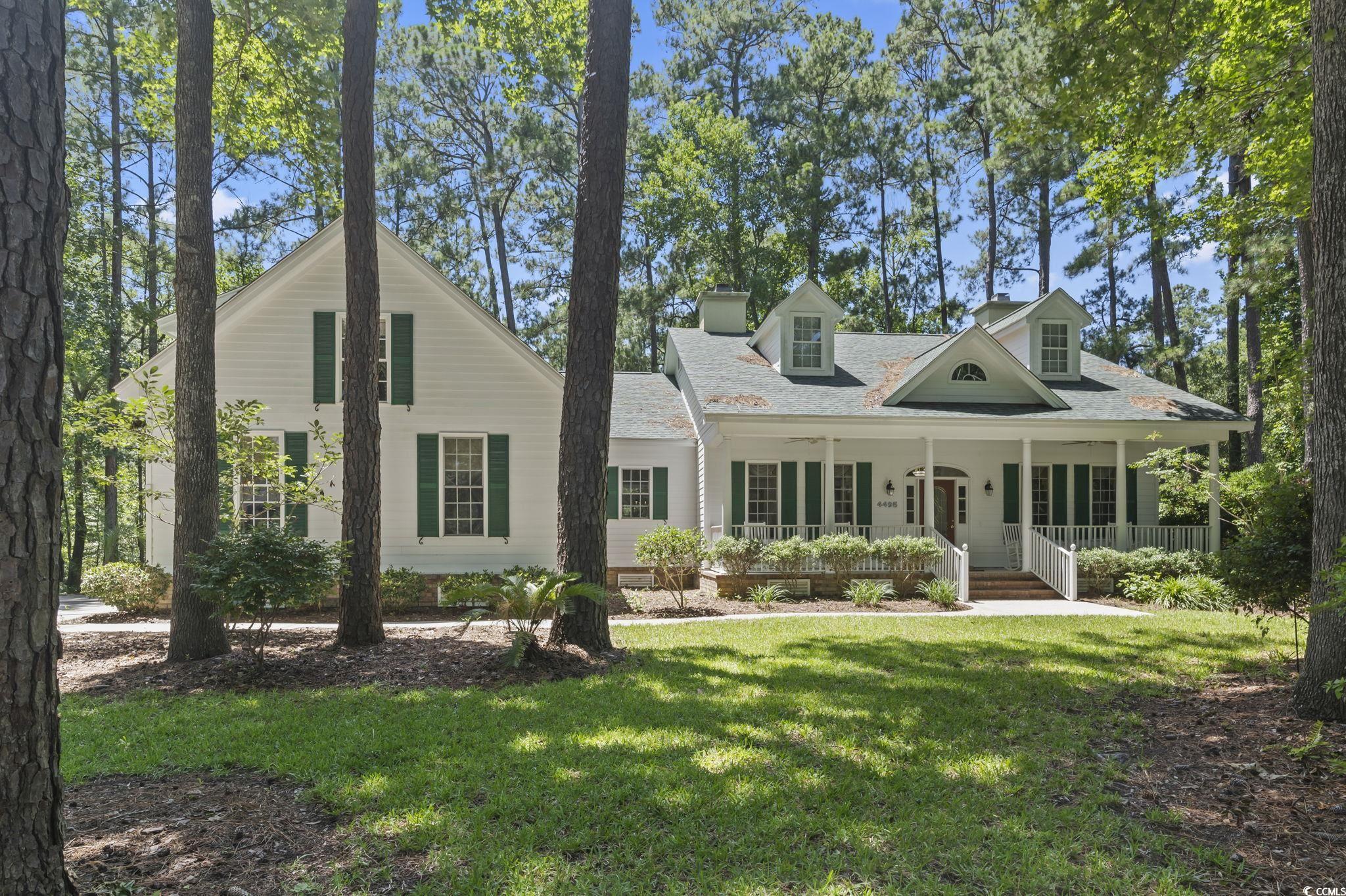 View of front of home with a porch, a front lawn, roof with shingles, and a chimney
