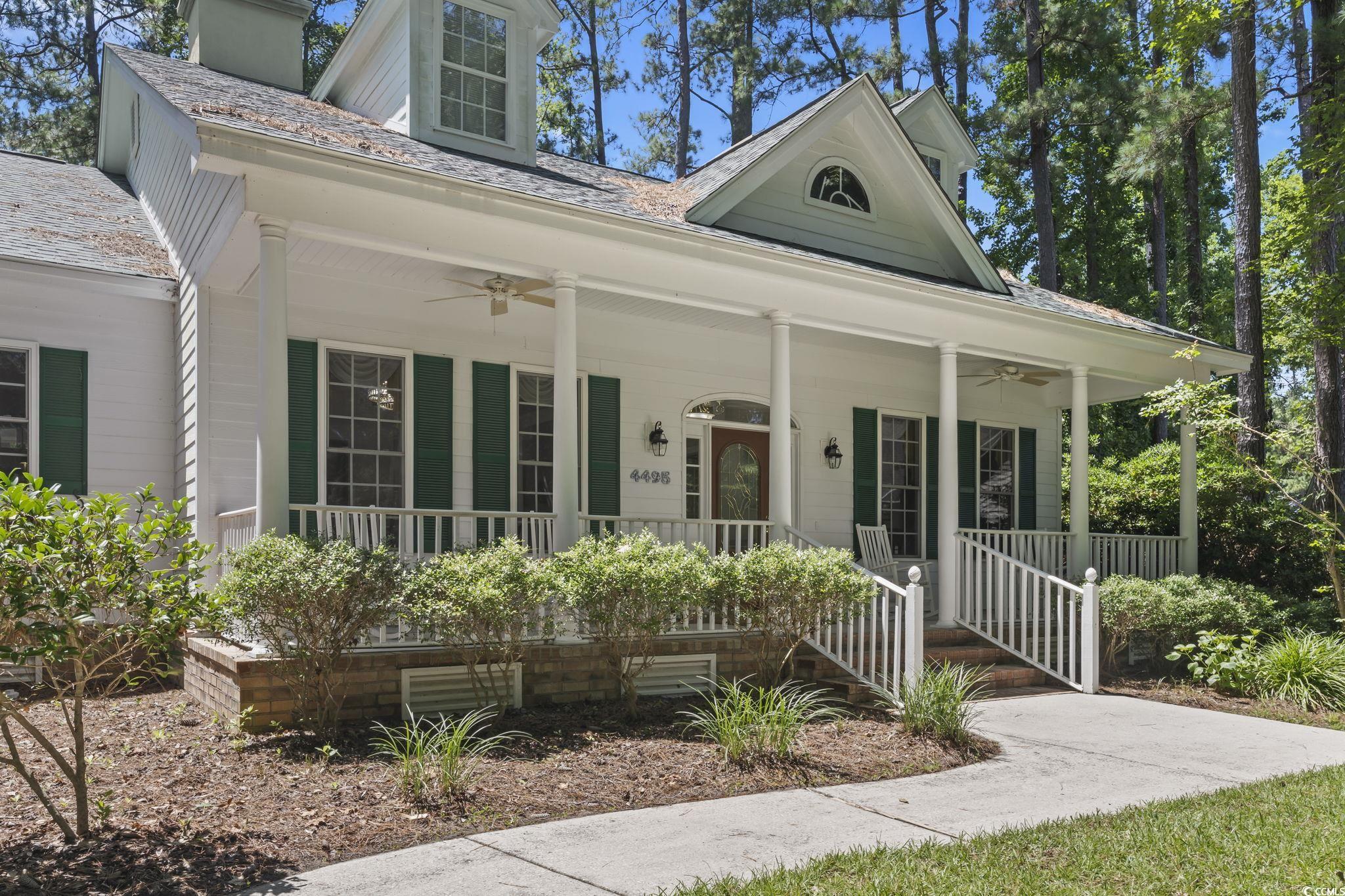 View of front of property featuring ceiling fan, covered porch, and a chimney