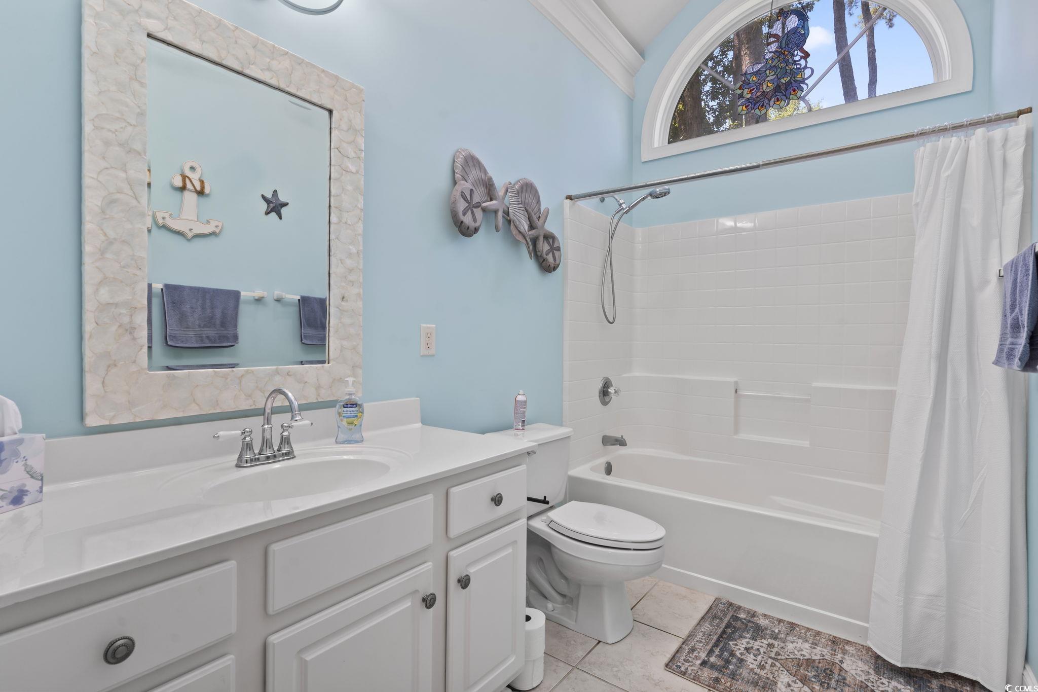 Full bathroom featuring tile patterned floors, vanity, and shower / bathtub combination with curtain