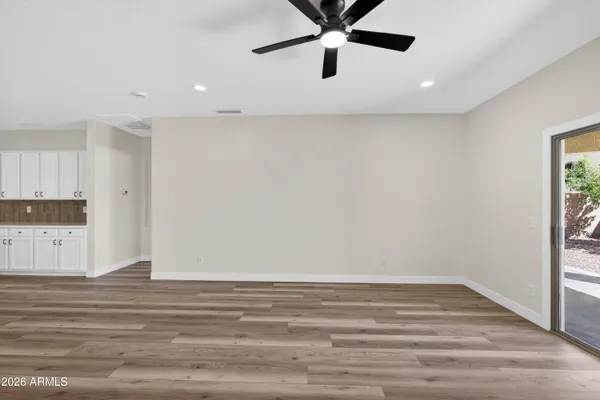 an empty room with wooden floor ceiling fan and window