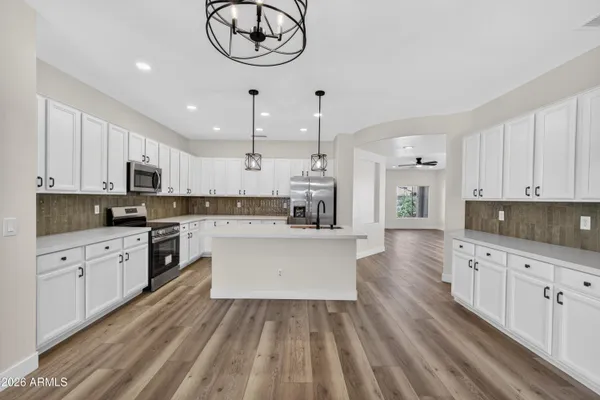 a kitchen with stainless steel appliances granite countertop a sink stove and white cabinets with wooden floor