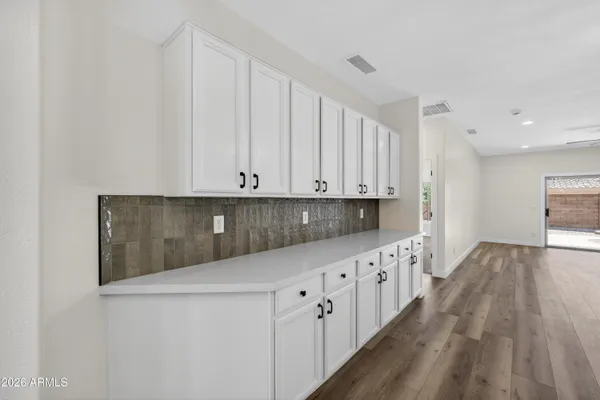 a view of a hallway with wooden floor and a bathroom