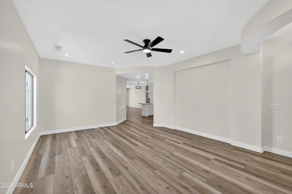 a view of an empty room with wooden floor and a window