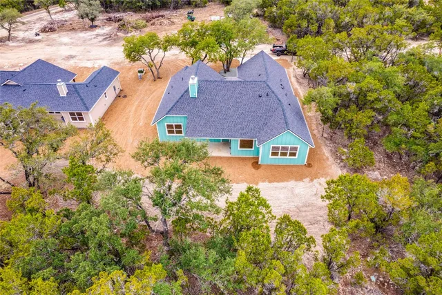 an aerial view of residential houses with outdoor space and trees