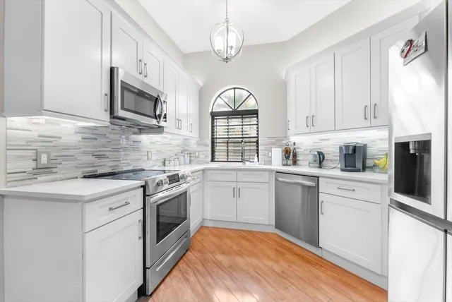 a kitchen with stainless steel appliances granite countertop a stove a sink and white cabinets