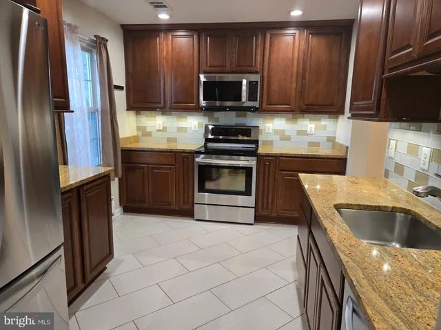 a kitchen with granite countertop a refrigerator stove and microwave