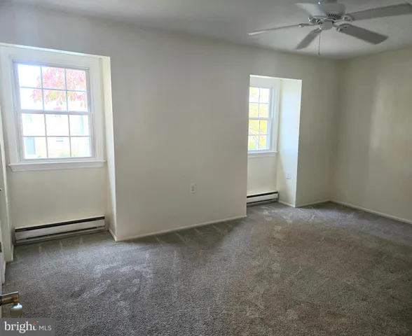 an empty room with windows and fan