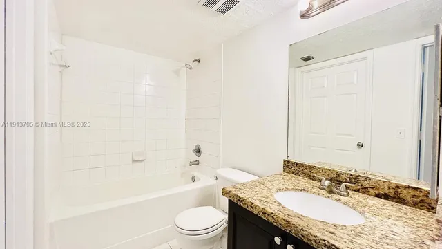 a bathroom with a granite countertop tub sink toilet and mirror