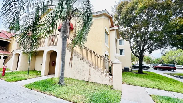 a front view of a house with a yard and palm trees