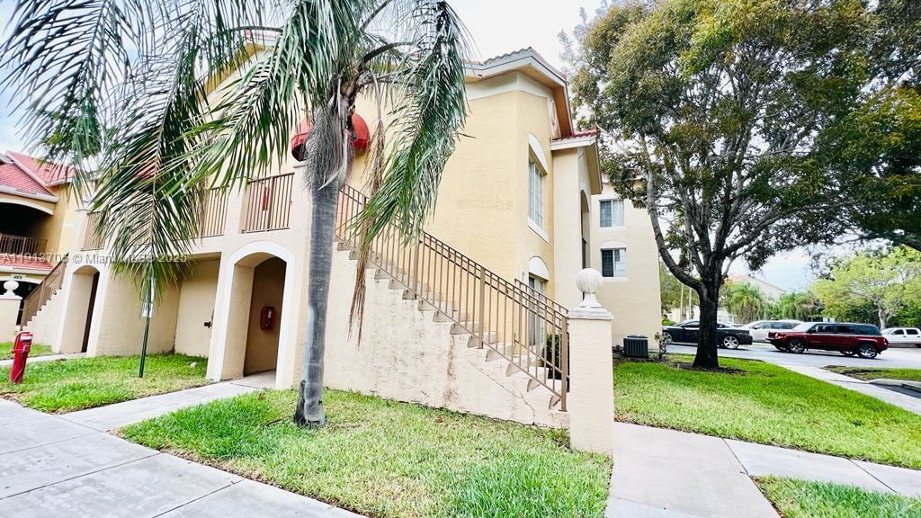 4115 San Marino Boulevard, Unit 101 West Palm Beach, FL 33409 - Photo 2 of 25 a front view of a house with a yard and palm trees