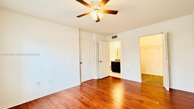a view of a room with wooden floor and a ceiling fan