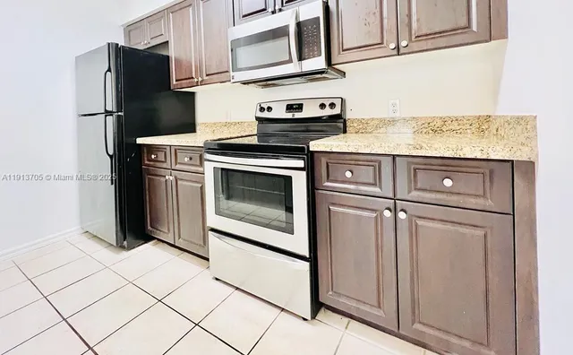 a kitchen with stainless steel appliances granite countertop a refrigerator stove and cabinets