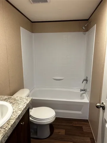 a bathroom with a granite countertop bathtub shower sink vanity and toilet