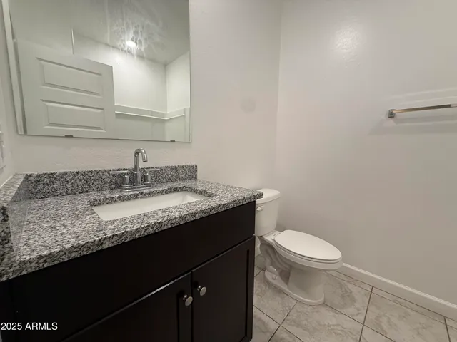 a bathroom with a granite countertop sink a toilet and shower