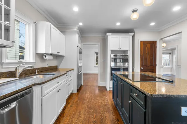 a large kitchen with granite countertop a large counter top a sink a window and stainless steel appliances