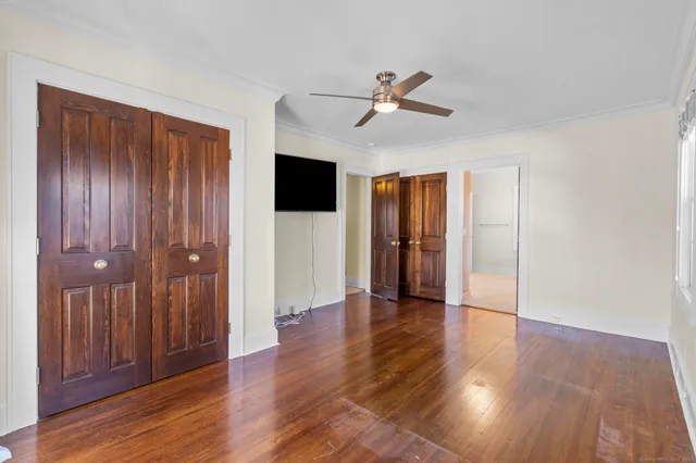 a view of empty room with wooden floor and fan