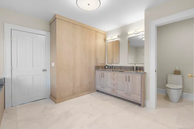 a bathroom with a granite countertop sink a toilet and a mirror
