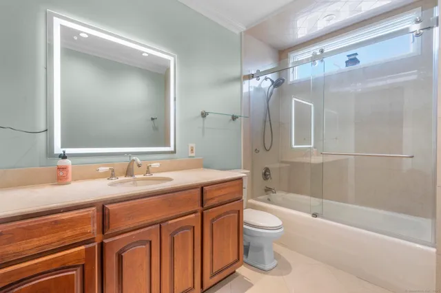 a bathroom with a granite countertop sink toilet a large mirror a bathtub and shower