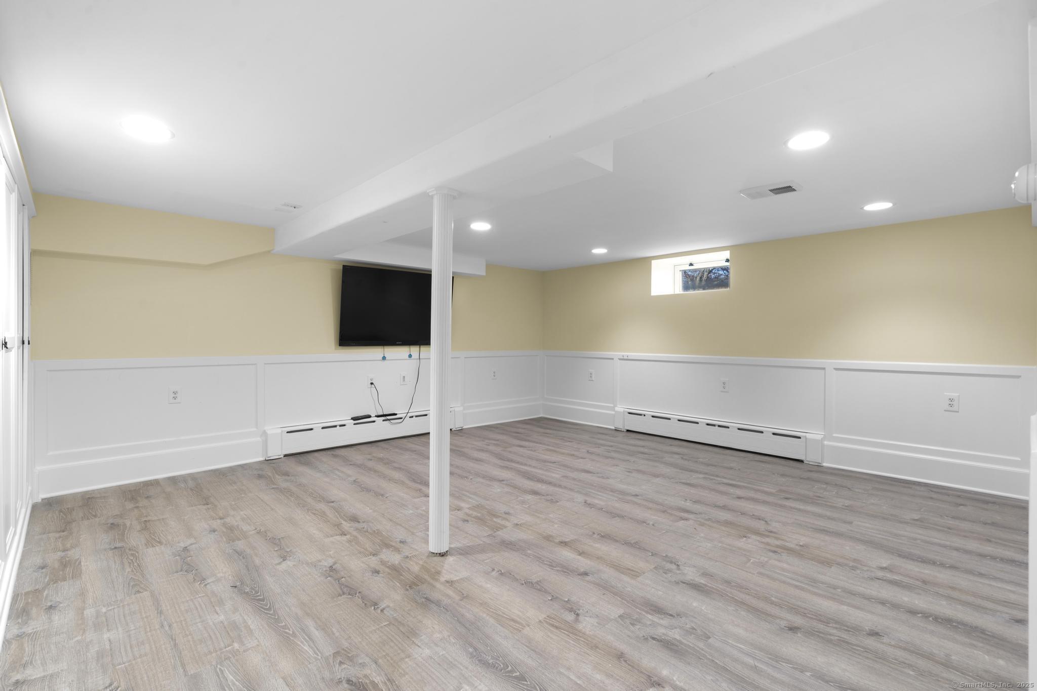 447 Reef Road Fairfield, CT 06824 - Photo 24 of 27 an empty room with wooden floor and mirror