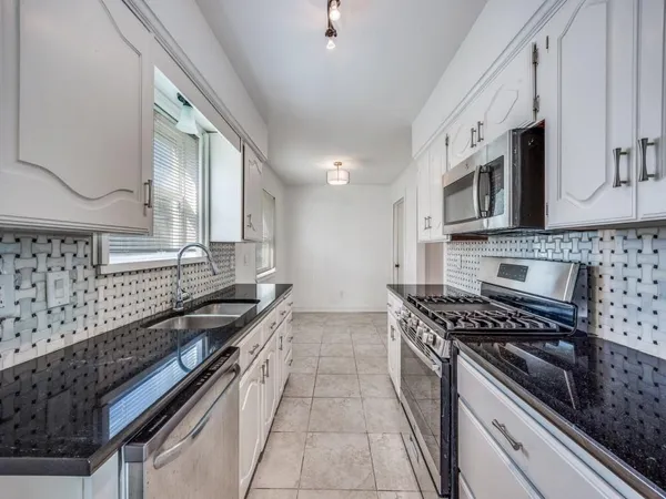 a kitchen with stainless steel appliances a sink a stove top oven a counter space and cabinets