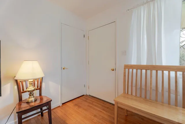 a view of a hallway with wooden floor and a bathroom