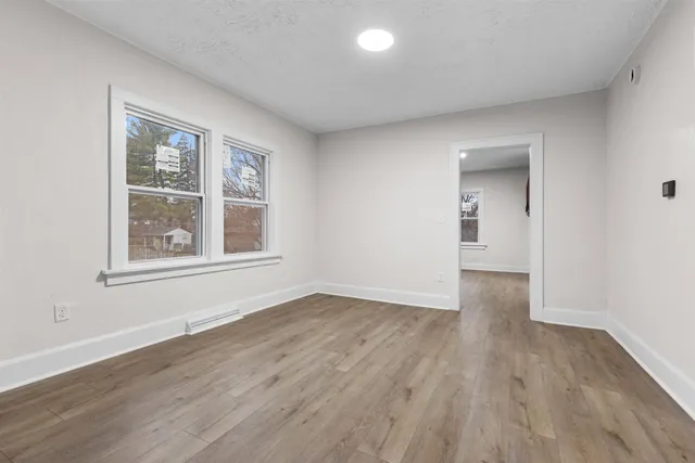 a view of an empty room with wooden floor and a window