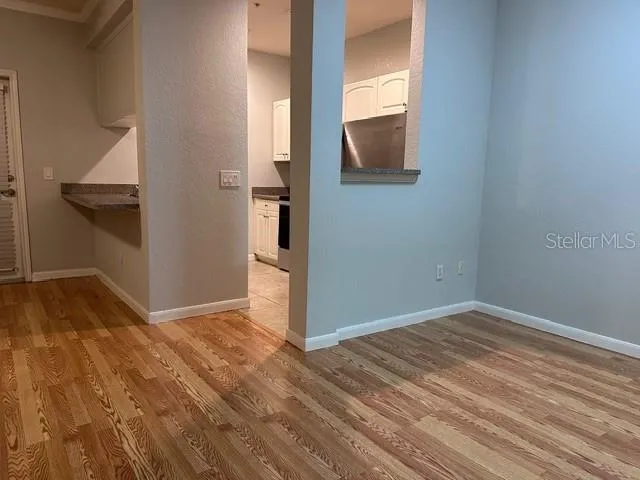 a view of kitchen and empty room with wooden floor