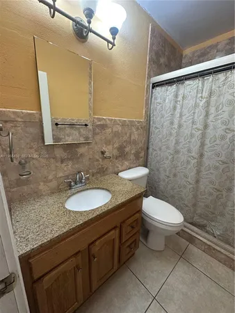 a bathroom with a granite countertop sink toilet and a mirror
