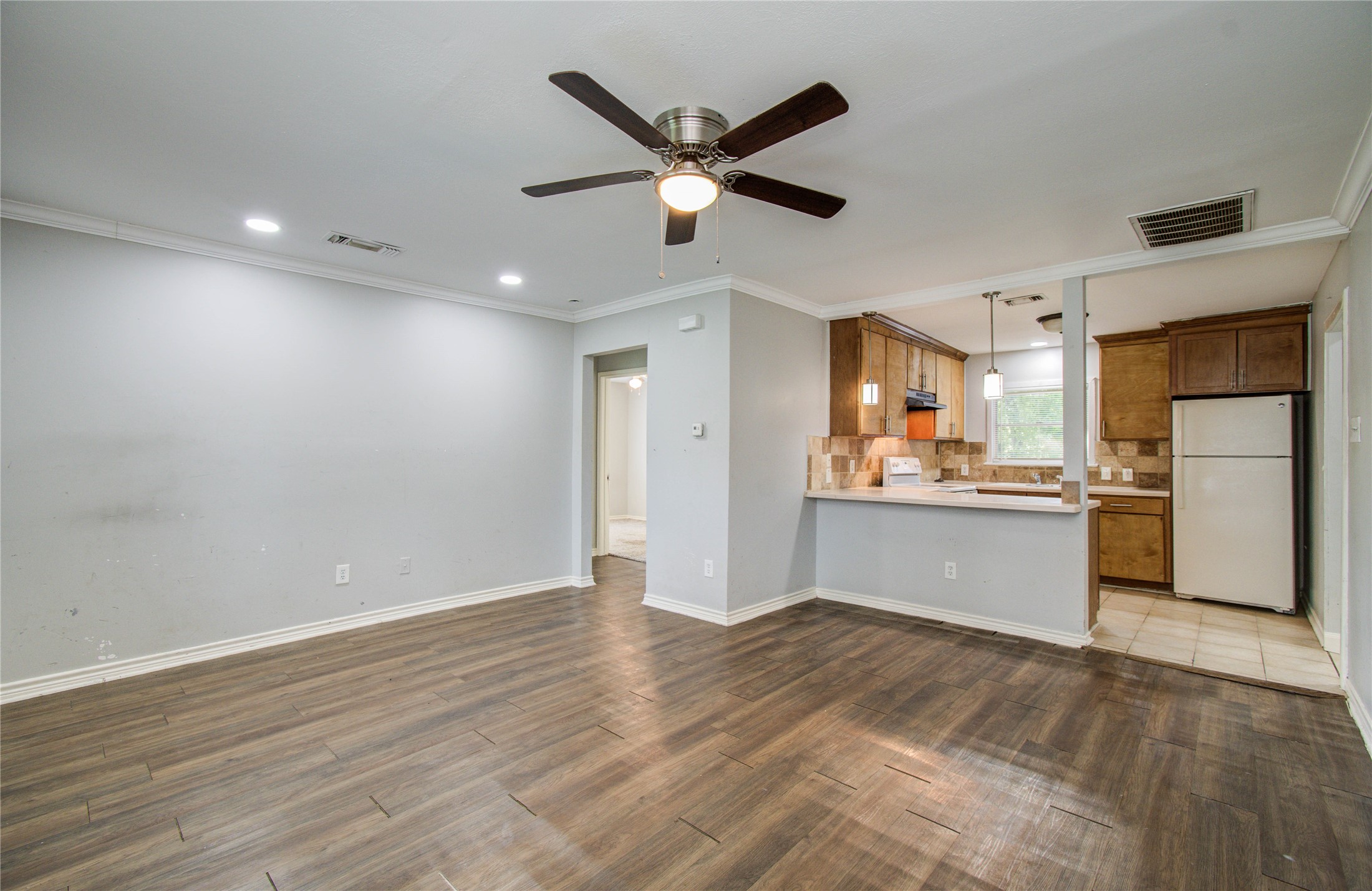 6830 New York Street Houston, TX 77021 - Photo 5 of 23 a view of a kitchen with wooden floor and a ceiling fan