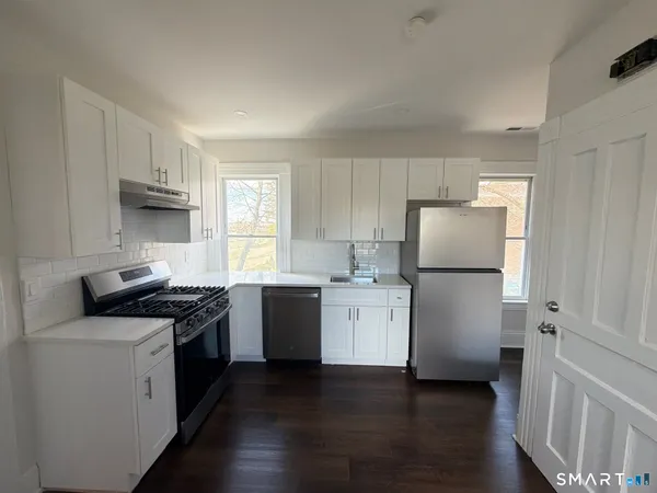 a kitchen with a refrigerator stove and wooden floor