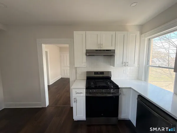 a kitchen with stainless steel appliances a stove and white cabinets
