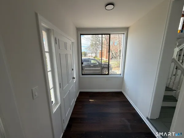 a view of a hallway with wooden floor and stairs