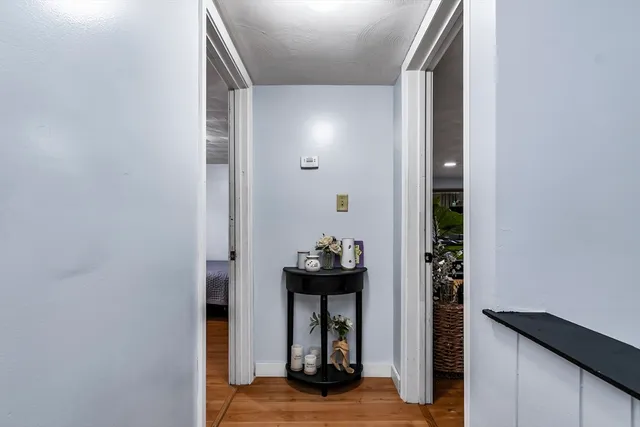 a view of a hallway with wooden floor and living room