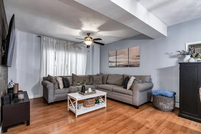 a living room with furniture a ceiling fan a lamp and a window