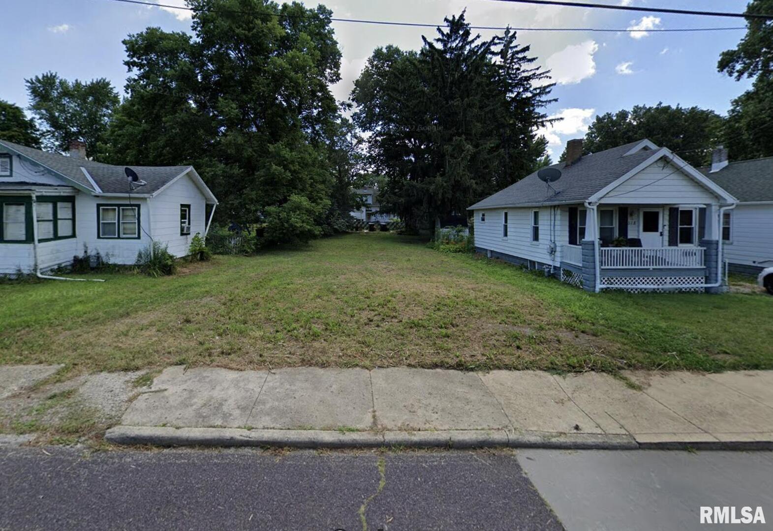 a view of a yard in front of a house with large windows