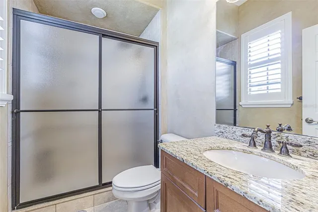 a bathroom with a granite countertop sink toilet and shower