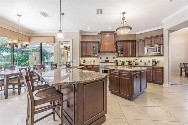 a kitchen with kitchen island granite countertop a sink counter and chairs