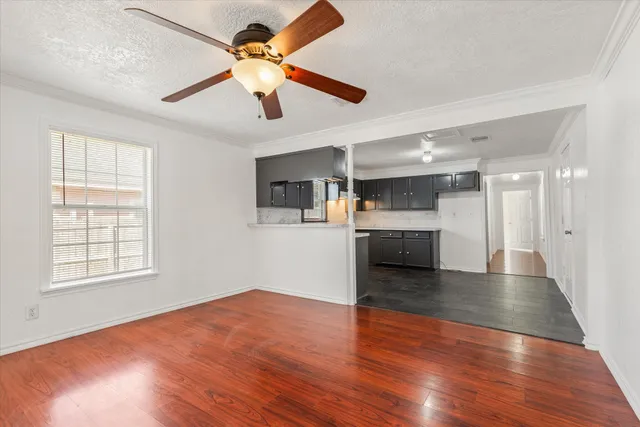 a view of an empty room with a window and wooden floor