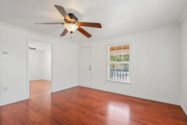 a view of empty room with wooden floor and fan
