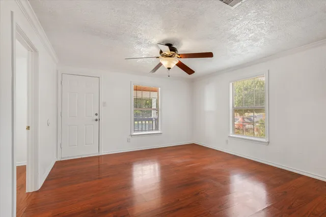 a view of an empty room with wooden floor and a window