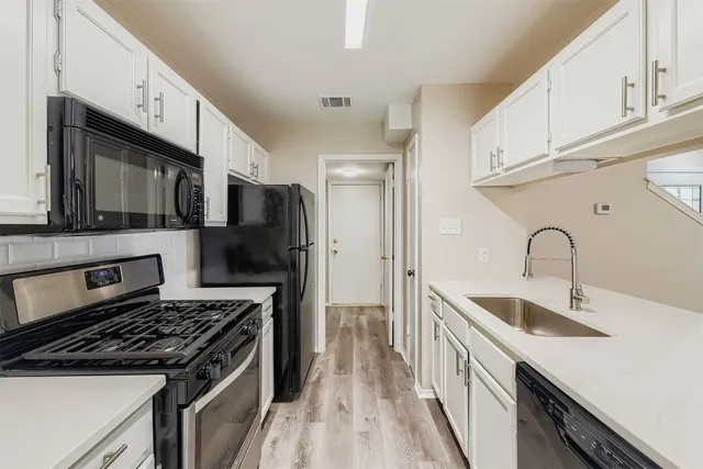 a kitchen with stainless steel appliances granite countertop a sink stove refrigerator and cabinets