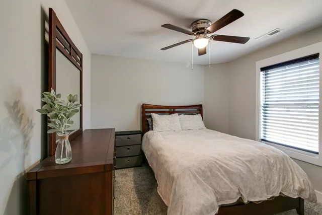 a bed sitting in a bedroom next to a window and a potted plant