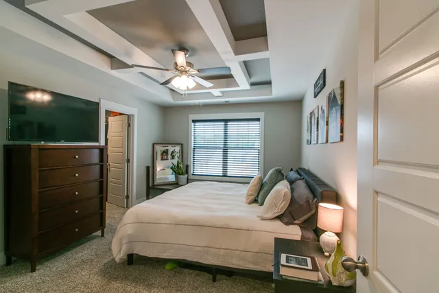 a bedroom with a bed and a flat tv screen on dresser