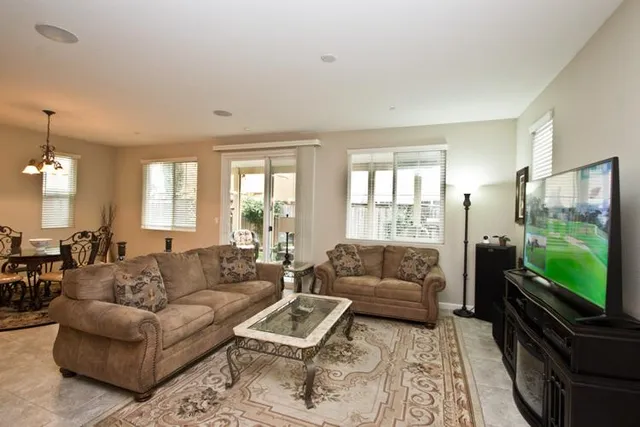 a living room with furniture flat screen tv and a large window