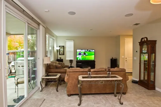 a living room with furniture a flat screen tv and a floor to ceiling window