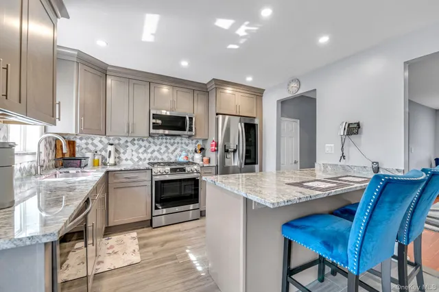 a kitchen with stainless steel appliances granite countertop a stove a sink a microwave a refrigerator and cabinets