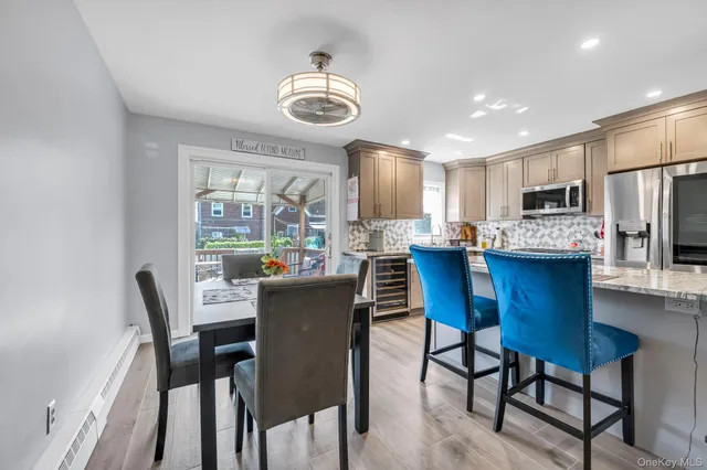 a dining room with stainless steel appliances kitchen island granite countertop a dining table chairs and a refrigerator