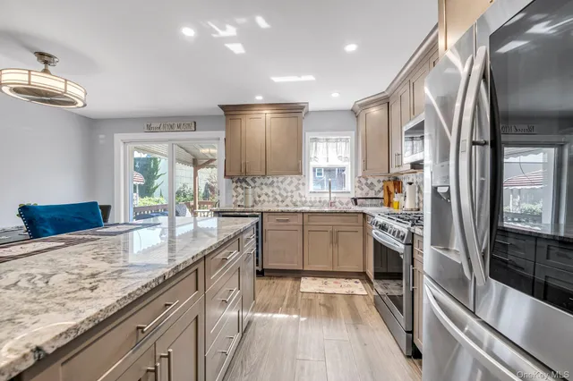 a large kitchen with granite countertop a sink stainless steel appliances and cabinets