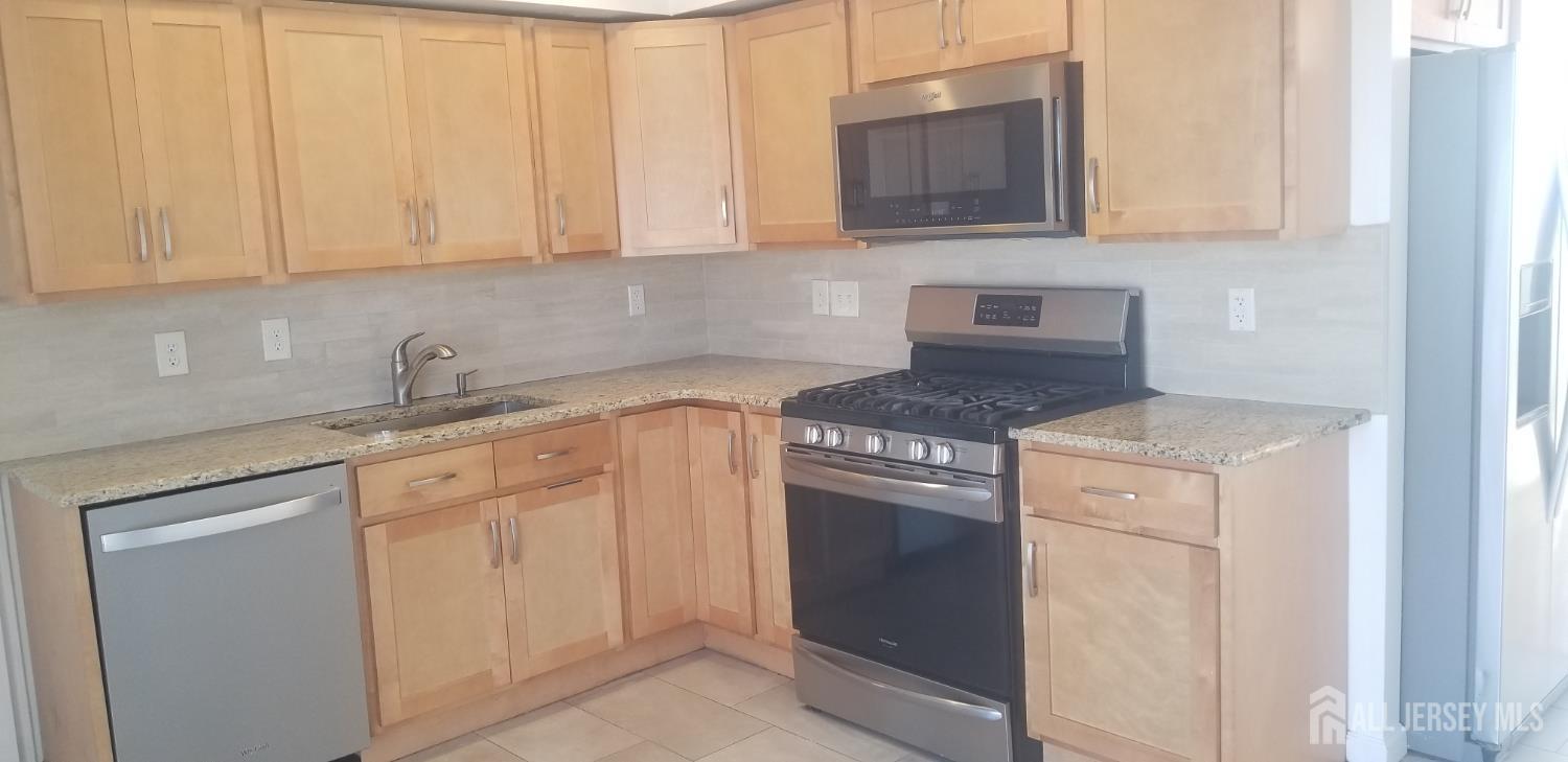 a kitchen with granite countertop white cabinets and stainless steel appliances